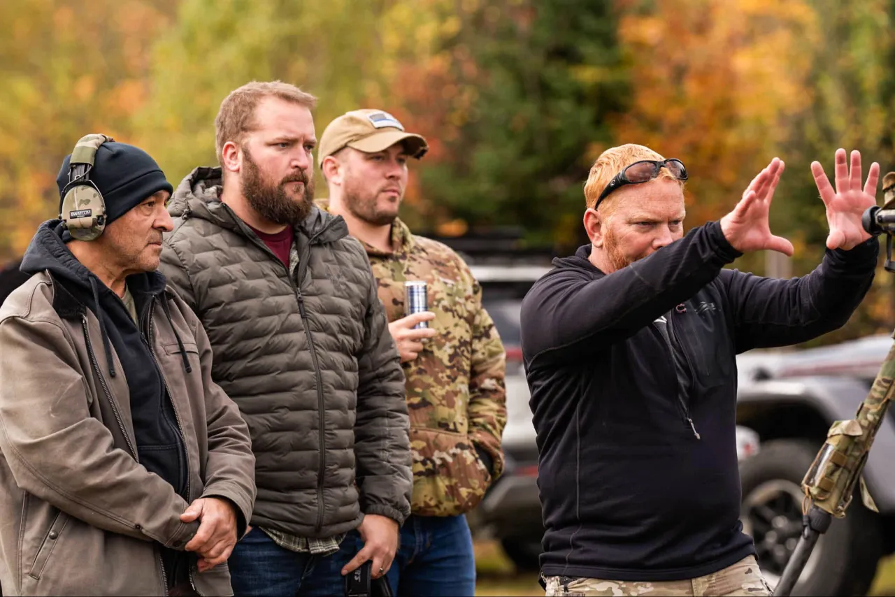 Instructor gesturing with both hands while explaining a concept to a group of students
