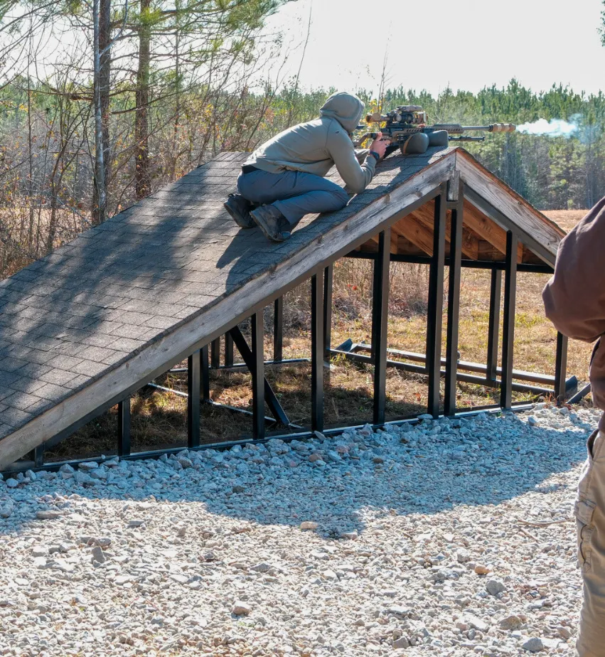 Shooter firing from a roof-shaped barricade at a match stage