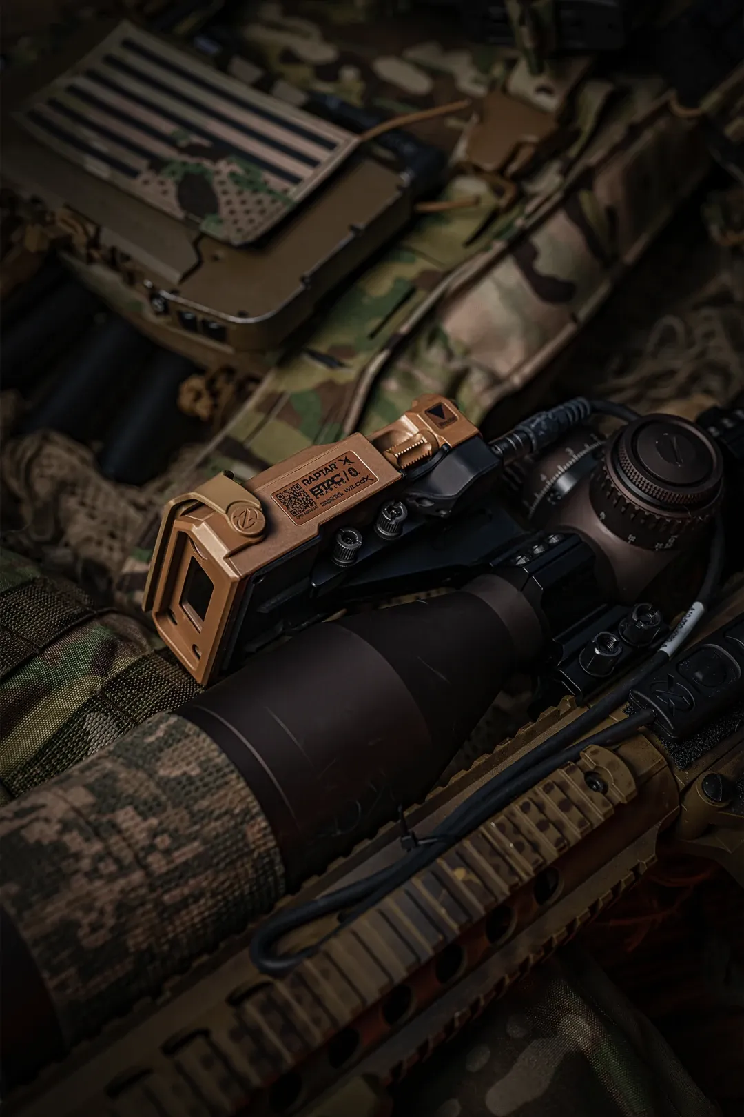 Close-up of a rifle scope with a tan rangefinding module mounted beside it