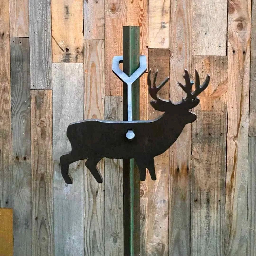 Elk-shaped steel target hanging on a post in front of a wooden fence