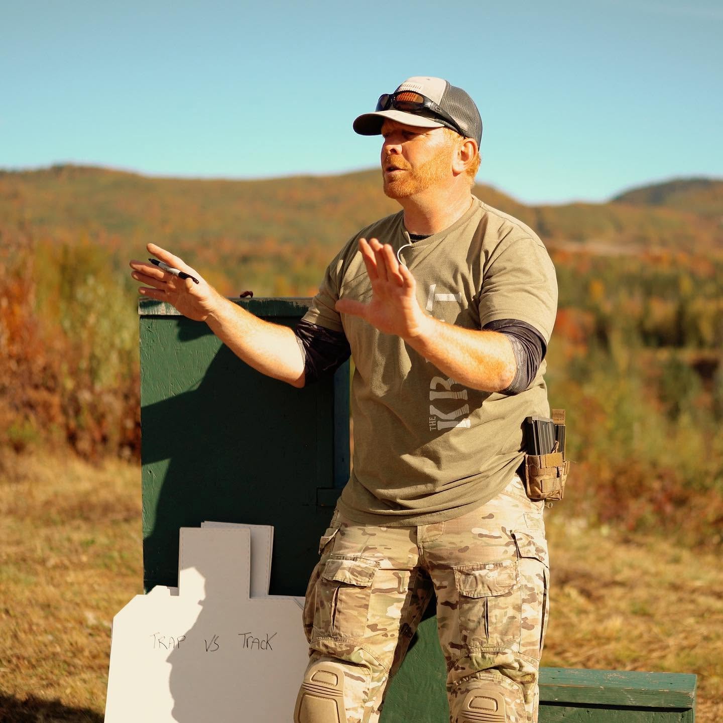 Instructor Mike giving hands-on coaching to a student in prone shooting position